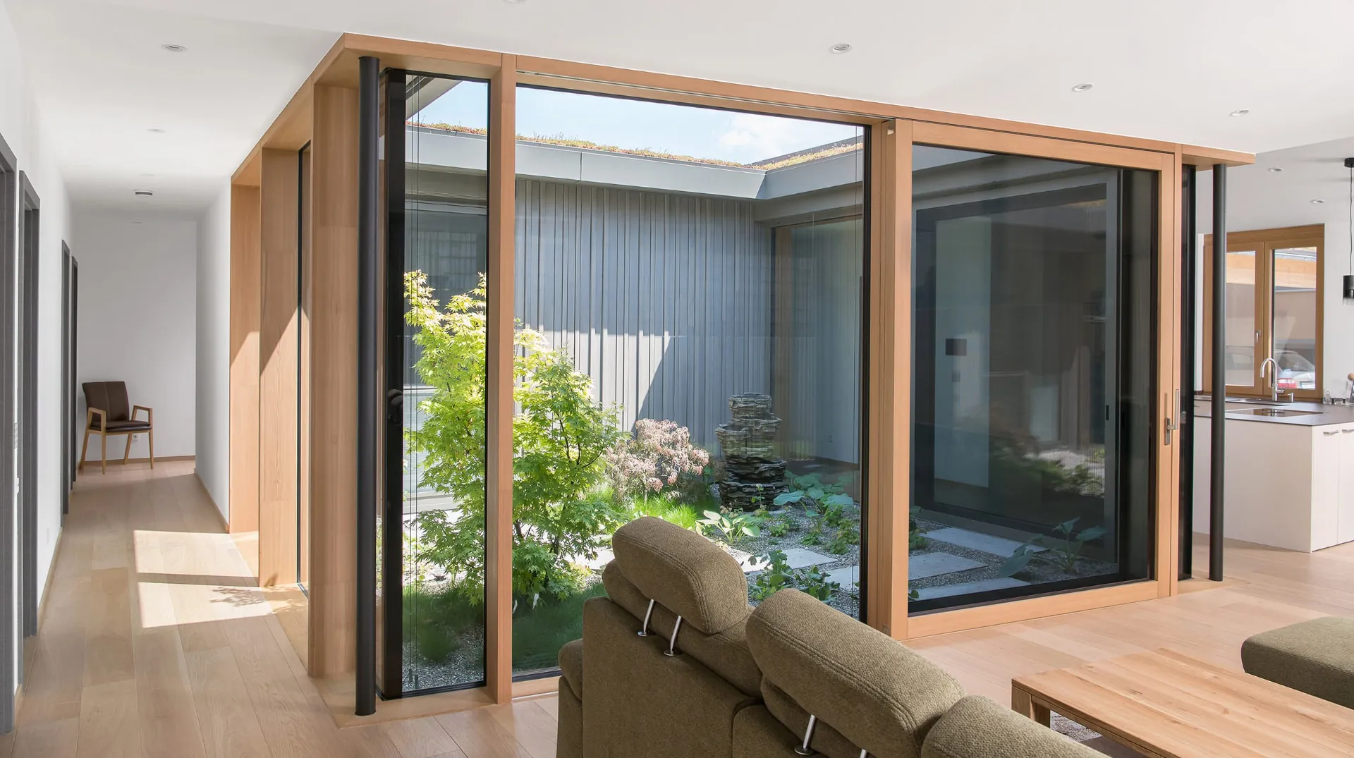 Salón abierto a un patio interior cerrado con fachada SKYWALL, con esquina de vidrio y hojas correderas